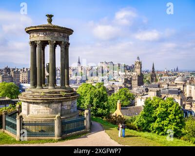 17. Mai 2024: Edinburgh, Schottland: Das Dugald Stewart Memorial auf dem Calton Hill mit Blick über Edinburgh bis zur Burg. Ein junges Paar, das auf die Aussicht blickt. Stockfoto