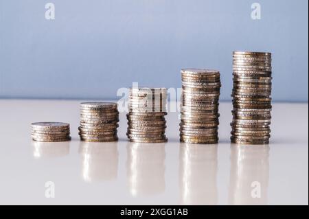 Fünf Stapel alter Silbermünzen bilden eine aufsteigende Grafik auf einer reflektierenden Oberfläche Stockfoto