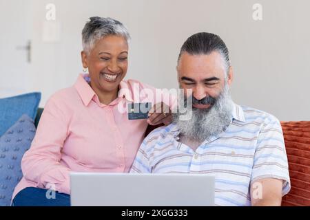 Mit Laptop und Kreditkarte, Seniorenpaar einkaufen online, lächeln zusammen Stockfoto