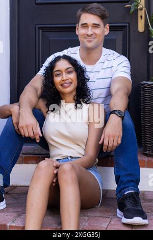 Lächelndes, junges Paar, das auf Stufen sitzt und die gemeinsame Zeit im Freien genießt Stockfoto