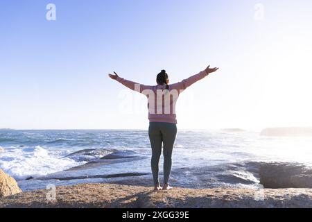 Auf Felsen am Meer stehend, Frau, die Arme streckt und die Natur genießt, Kopierraum Stockfoto