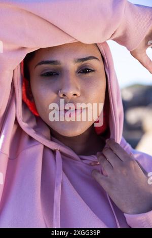 Mit einem rosafarbenen Kapuzenpullover posiert die Frau selbstbewusst und zeigt natürliche Schönheit und Selbstvertrauen Stockfoto