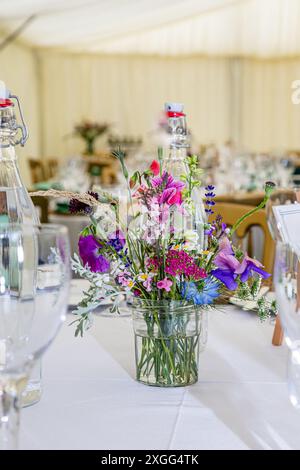 Tische mit Gläsern und Blumen in einem Festzelt für eine Party Stockfoto