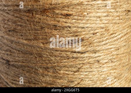 Nahaufnahme einer natürlichen Jute-Garnspule, die die raue, fasrige Textur zeigt. Die organische Qualität und die komplizierte Webstruktur zeigen die ineinander verflochtene Stk Stockfoto