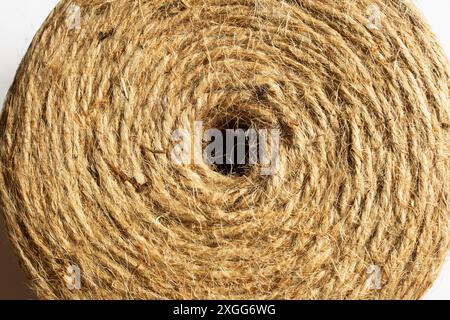 Nahaufnahme einer natürlichen Jute-Garnrolle, von oben betrachtet, die das zentrale Loch zeigt und seine komplizierte, fasrige Textur zeigt, die das DE einfängt Stockfoto