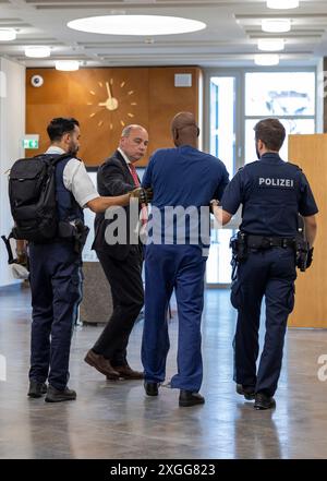 Aschaffenburg, Deutschland. Juli 2024. Der Angeklagte (2. Von rechts) wird von seinem Anwalt Jens Goymann (2. Von links) begrüßt, als er von zwei Polizisten in den Gerichtssaal des Amtsgerichts Aschaffenburg gebracht und mit Handschellen und Fesseln gefesselt wird. Der Mann, dem der Versuch vorgeworfen wurde, seine Ex-Frau zu ermorden, gab vor Gericht zu, dass er die Mutter seiner Kinder angegriffen habe. Quelle: Heiko Becker/dpa/Alamy Live News Stockfoto