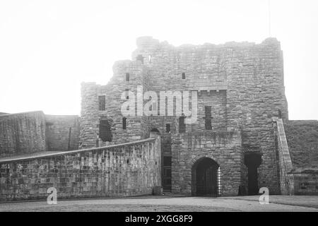 Ein Schwarzweißfoto einer alten Steinburg mit teilweise Ruinen. Die Burg verfügt über mehrere Ebenen, bogenförmige Türen und eine steinerne Wanne Stockfoto