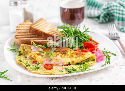 Gesundes Frühstück. Omelette mit Käse, Tomaten und grünen Kräutern. Omelette, Salat und Toast. Keto, ketogenes Mittagessen. Stockfoto