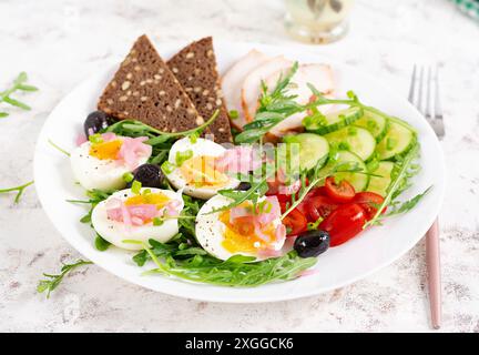 Gesundes Frühstück. Gekochtes Ei, Hähnchenschinken, Brot und frischer Salat. Keto-Frühstück. Stockfoto
