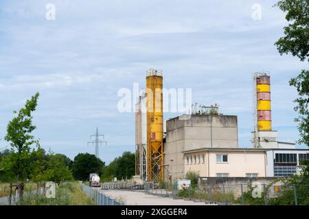 Ein Betonwerk mit hohen gelben Silos und einem vorbeifahrenden LKW. Stockfoto