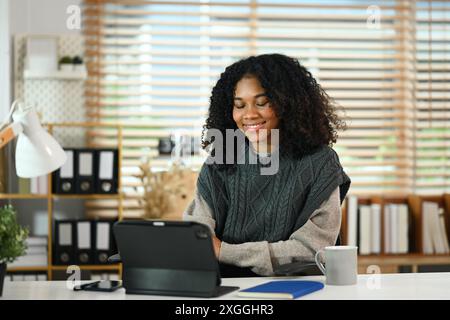 Porträt einer afroamerikanischen Freiberuflerin, die mit einem digitalen Tablet an einem komfortablen Arbeitsplatz arbeitet Stockfoto