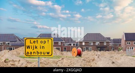 Verkehrsschild mit dem niederländischen Text für „Achtung - Wohngebiet im Bau“ vor einer Baustelle mit Villen in den Niederlanden Stockfoto