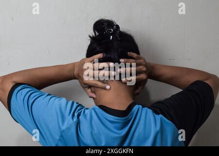 Rückansicht eines Mannes, der seine Ohren über dem Kopf auf beigefarbenem Hintergrund bedeckt Stockfoto