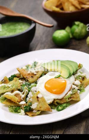 Chilaquiles, mexikanisches Frühstück. Totopos mit Salsa verde, Spiegelei und Avocado. Stockfoto