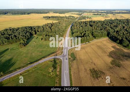 Eine ländliche Straßenkreuzung, umgeben von Feldern und Wäldern. Stockfoto