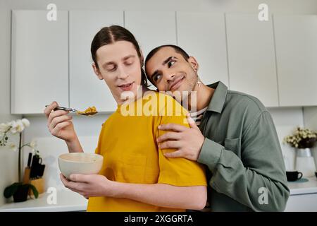 Ein junges schwules Paar frühstückt in seinem modernen Apartment und teilt einen zärtlichen Moment mit einer Umarmung. Stockfoto