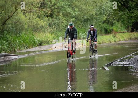 Chesham, Großbritannien. Juli 2024. In Chesham in Buckinghamshire bewegen sich die Radfahrer sanft durch das Hochwasser. Der Fluss Schach ist übergelaufen, was auf hohe Strömungen und Verstopfungen durch Vegetationswachstum zurückzuführen ist. Quelle: Maureen McLean/Alamy Live News Stockfoto