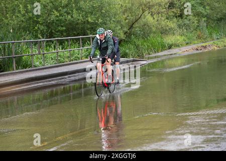 Chesham, Großbritannien. Juli 2024. In Chesham in Buckinghamshire bewegen sich die Radfahrer sanft durch das Hochwasser. Der Fluss Schach ist übergelaufen, was auf hohe Strömungen und Verstopfungen durch Vegetationswachstum zurückzuführen ist. Quelle: Maureen McLean/Alamy Live News Stockfoto