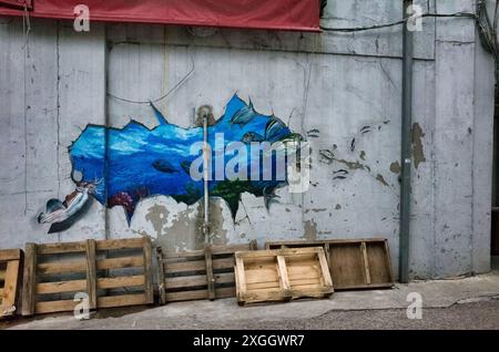 Lebendiges Unterwasser-Wandgemälde auf verwitterter Wand mit Holzpaletten, das urbanen Verfall und künstlerischen Ausdruck vereint Stockfoto