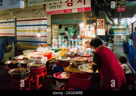 Lebhafter koreanischer Marktstand mit verschiedenen Beilagen und einem Verkäufer in Rot Stockfoto