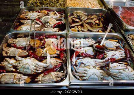 Frisch zubereitete Krabben und Meeresfrüchte in Soße, ausgestellt auf Metalltabletts auf einem Markt Stockfoto