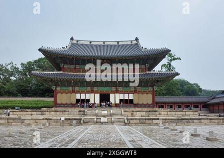 Reich verziertes koreanisches Palastgebäude mit traditioneller Architektur, umgeben von einem Innenhof aus Stein und Besuchern Stockfoto