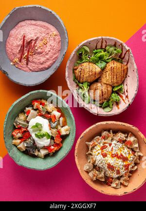 Schüsseln mit vegetarischen Speisen auf einem leuchtenden rosa-orangen Hintergrund. Gesundes Abendessen. Buddha-Schüssel mit frischem Gemüse und Hummus. Stockfoto