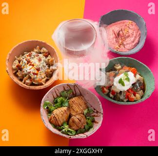 Set vegetarischer Schalen auf einem lebhaften Pinkorange Hintergrund mit einem Explosionsgetränk. Modernes Konzept. Stockfoto