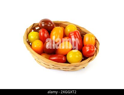 Verschiedene Tomatensorten in einem gewebten Korb, isoliert auf weißem Hintergrund. Stockfoto