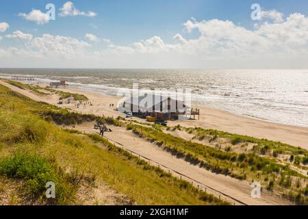 Blick von den Dünen von Petten aan Zee, Provinz Noord-Holland, Niederlande, entlang des Strandes mit Strandbar und Rettungsstation Stockfoto