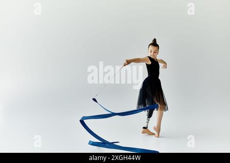 Eine junge Turnerin mit einer Beinprothese tritt mit einem blauen Band auf. Stockfoto