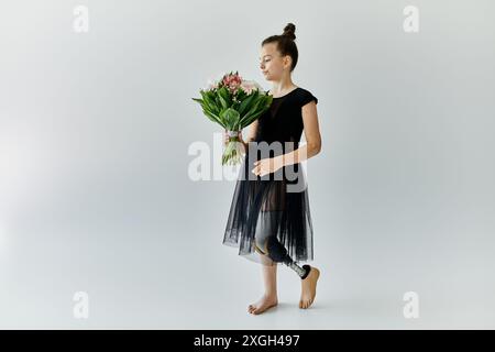 Ein junges Mädchen mit einer Beinprothese hält einen Blumenstrauß in einem Atelier. Stockfoto