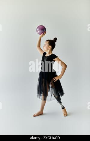 Ein junges Mädchen in schwarzem Trikot und Rock übt Gymnastik mit einer Beinprothese. Stockfoto