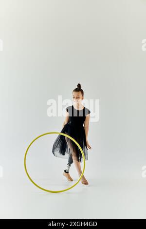 Ein junges Mädchen mit einer Beinprothese führt Gymnastik mit einem Hula Hoop durch. Stockfoto