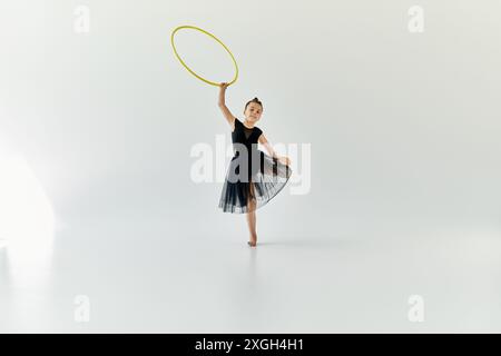 Ein junges Mädchen mit einer Beinprothese übt Gymnastik mit einem Hula Hoop in einem Studio. Stockfoto