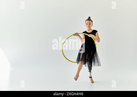 Ein junges Mädchen mit einer Beinprothese führt Gymnastik mit einem Hula Hoop durch. Stockfoto