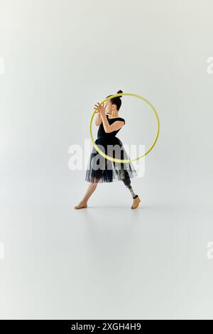 Ein junges Mädchen mit einer Beinprothese führt Gymnastik mit einem Hula Hoop durch. Stockfoto