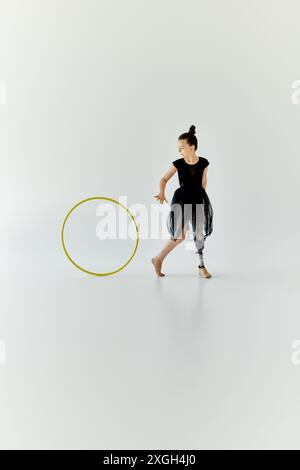 Ein junges Mädchen mit einer Beinprothese übt Gymnastik mit einem Hula Hoop. Stockfoto