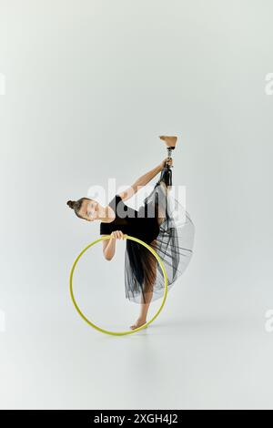 Ein junges Mädchen mit einer Beinprothese führt eine Gymnastik-Routine mit einem Reifen durch. Stockfoto