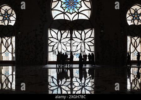 Abu Dhabi, VAE - 4. Januar 2024: Silhouettenfiguren in der kunstvoll verzierten Moschee. Stockfoto