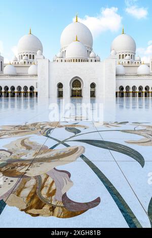 Abu Dhabi, VAE – 4. Januar 2024: Elegante Bögen und Kuppeln der Scheich-Zayed-Moschee spiegeln sich auf ihrem reich verzierten Innenhof. Stockfoto