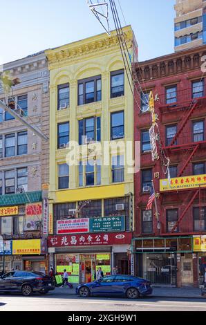 NYC Chinatown: 63 East Broadway ist ein fünfstöckiges, gelb lackiertes Backsteinloft-Gebäude mit Apartments über zwei Geschäftsgeschossen. Stockfoto