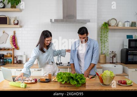 Glückliches Paar, das zu Hause in der Küche steht, ein köstliches Abendessen zubereitet, verheiratete Paare unterhalten sich, genießen warme Gespräche und den Prozess der Koh Stockfoto