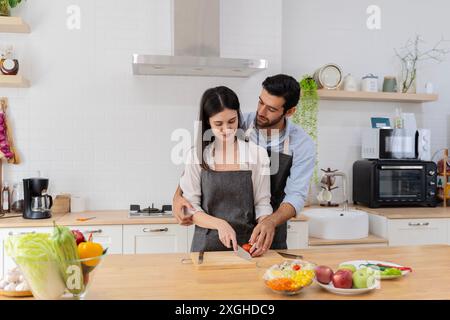 In der Küche bereitet ein glückliches Paar gesundes Essen, viel Gemüse zu, ein Mann jongliert mit Früchten und bringt ihren Freund zum Lachen. Süße Jungs ich Stockfoto