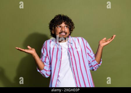 Portraitfoto eines arabischen Mitarbeiters in gestreiftem lässigem Hemd und Brille versagt zuckte Schultern isoliert auf khakifarbenem Hintergrund Stockfoto