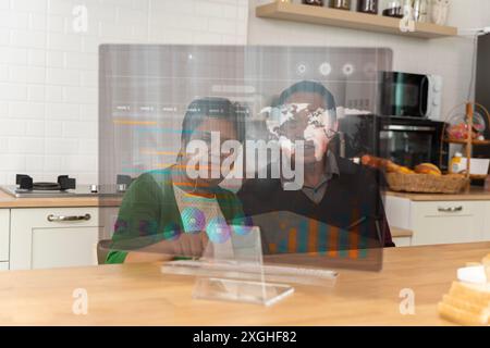 Glückliches Seniorenpaar, das einen Laptop benutzt, während er einen Urlaub zu Hause plant. Glückliches altes Paar, das sich mit dem Laptop unterhält und zusammen frühstückt, überrascht begeistert Stockfoto