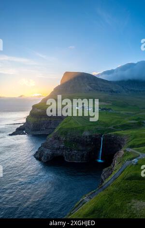 Blick aus der Vogelperspektive auf den Mulafossur-Wasserfall mit dem kleinen Dorf Gasadalur. Vagar Island, Färöer Inseln, Dänemark, Europa. Stockfoto