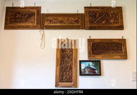 Geschnitzte Holzstücke hängen an einer Wand in einer Werkstatt in Srinagar. Kaschmir ist bekannt für seine exquisite Holzschnitzerei, ein Handwerk, das über Generationen weitergegeben wurde. Aus strapazierfähigem Walnussholz kreieren erfahrene Handwerker komplizierte Blumenmuster, geometrische Designs und traditionelle Motive. Diese akribische Arbeit, die auf Möbeln, dekorativen Tafeln und Souvenirs zu sehen ist, zeigt das kulturelle Erbe der Region. Ghulam Nabi Zargar, ist ein Meisterschnitzer, der detaillierte Entwürfe auf eine Walnussholz-Holzoberfläche graviert. Das Licht hebt die komplizierten Muster hervor, erweckt die Kunst zum Leben und reflektiert das e Stockfoto