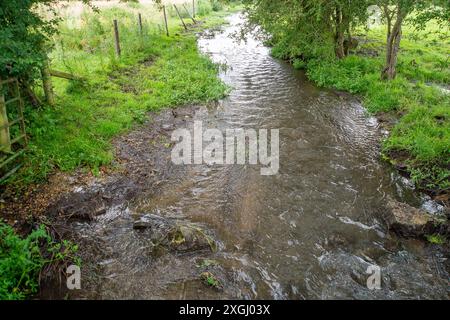 Chalfont St Giles, Großbritannien. Juli 2024. Das hübsche Dorf Chalfont St Giles in Buckinghamshire wurde als das „stinkendste Dorf Großbritanniens“ bezeichnet. Seit Januar dieses Jahres leitet das Wasser der Themse Abwässer aus den Amersham Balacing Tanks in den Fluss Misbourne (im Bild), einen wertvollen Kreidefluss, der mehr als 3.500 Stunden durch Chalfont St Peter fließt. Der Chalfont St Giles Parish Council hat nun den Zugang zum Kinderspielplatz, zum Dorfteich und zur Brücke über den Fluss Misbourne gesperrt, um die Dorfbewohner davon abzuhalten, mit einer möglichen Verschmutzung in Kontakt zu kommen. Der Teufel Stockfoto