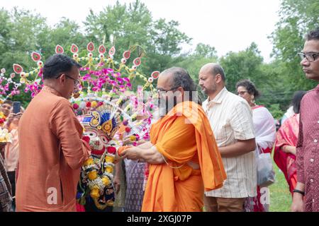 Swami Balgopal, ein Priester und Mönch, trägt eine Statue des hinduistischen Gottes Balaram vom Tempel zu einer Zeltfeier vor Beginn des Ratha Yatra 2024. Stockfoto